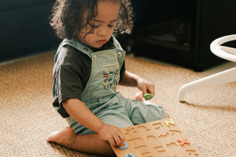 A toddler fitting pieces into a wooden letter board