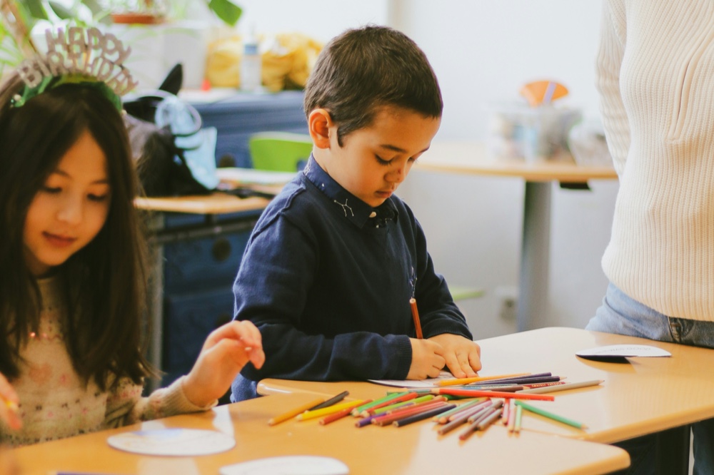 Children drawing at desks in a bright classroom
