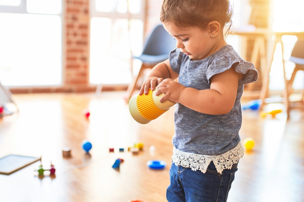 A toddler playing with toys in a bright open room