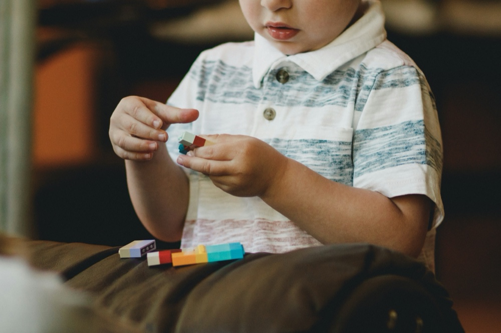 A child's hands sorting small coloured blocks